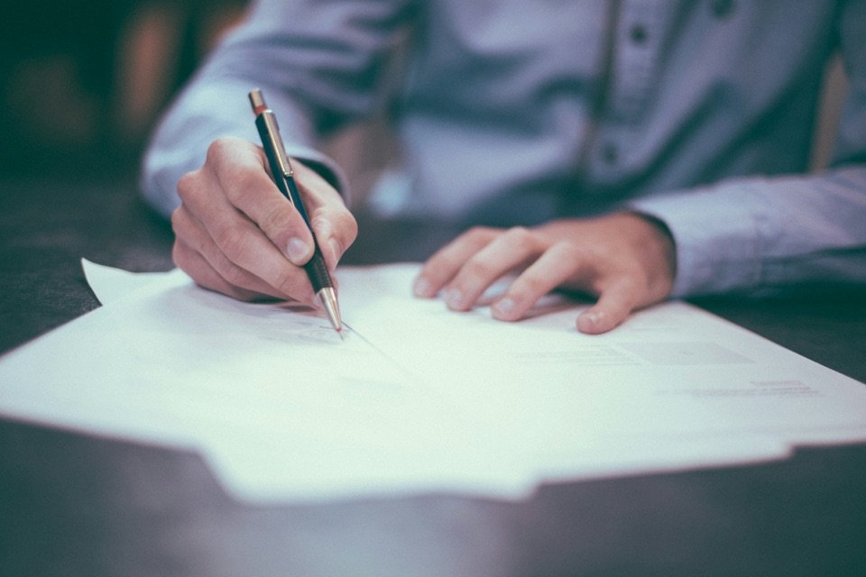 Un homme signe un document posé sur son bureau.