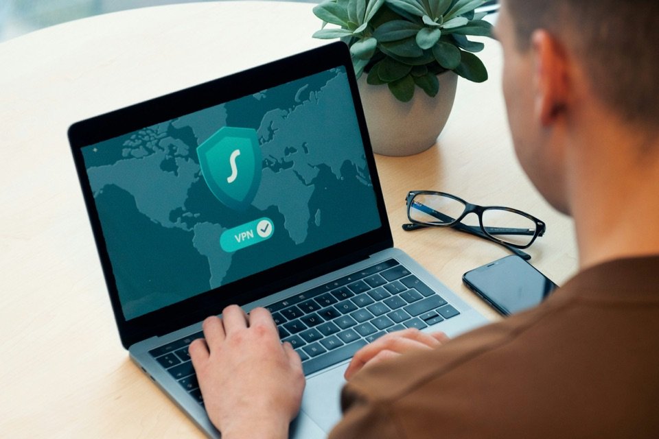 Un homme travaille sur un ordinateur portable qui affiche un bouclier de protection.